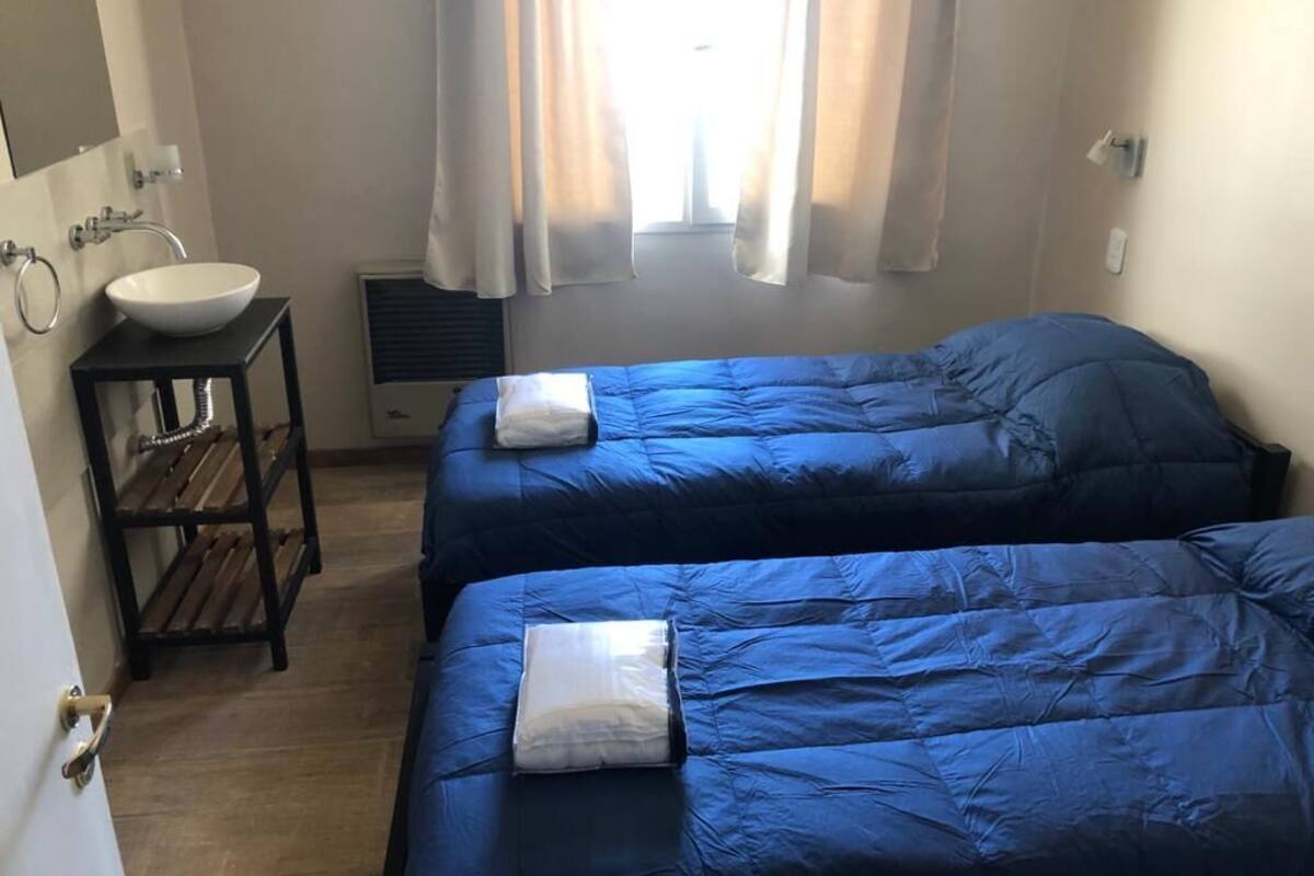 Une chambre avec deux lits, un lavabo et une fenêtre avec des rideaux.