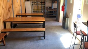 Una habitación amplia con bancos de madera, una zona de cocina y un extintor.