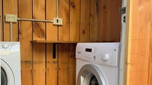 Un cuarto de lavado con paredes de madera y una lavadora.