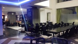 A modern conference room with a glass table and black chairs, a clock on the wall, and a plant in the corner. - Lynt Hotel Makassar (Makassar)