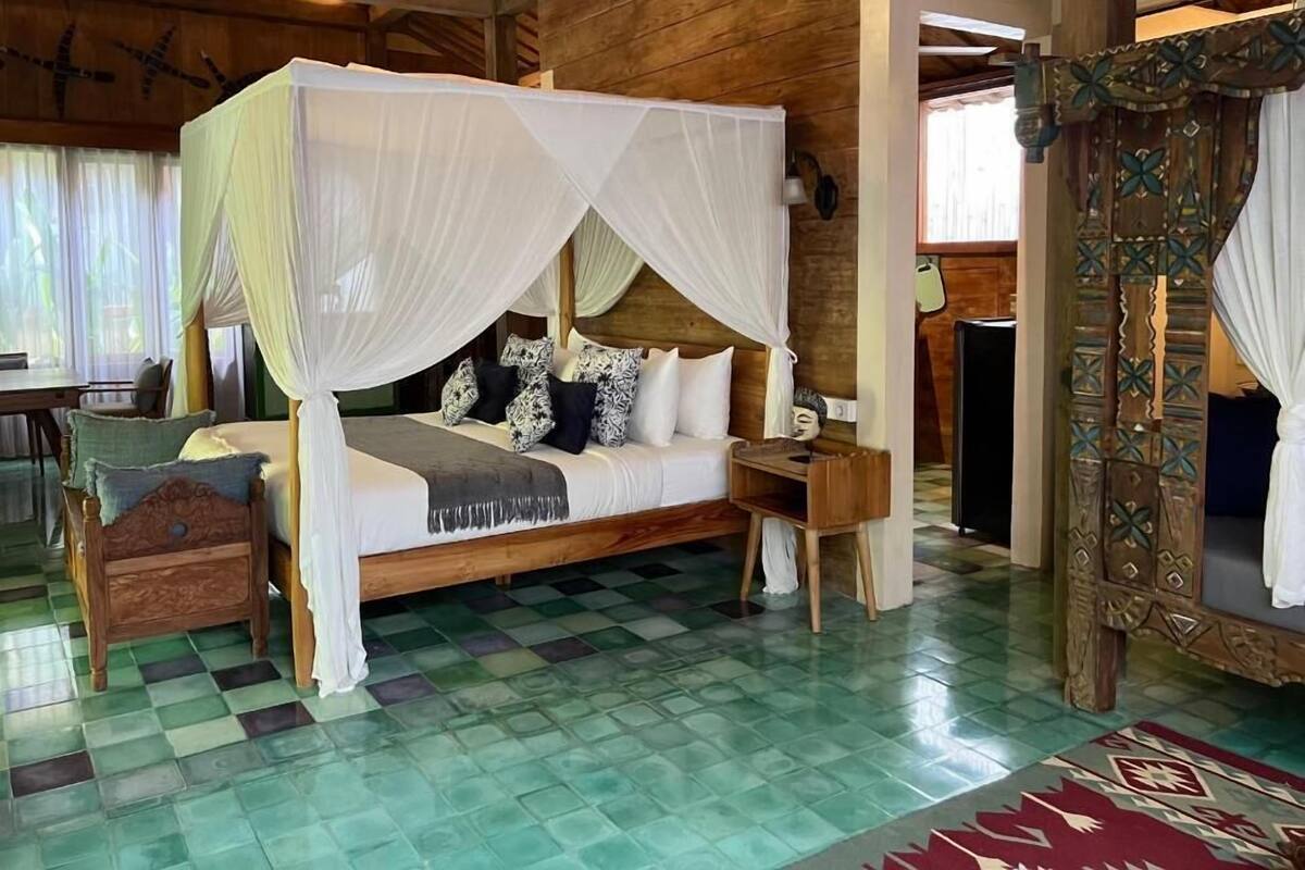A four-poster bed with a canopy, a wooden nightstand, a small chest of drawers, and a patterned rug.
