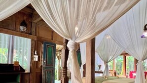 A bedroom with a large bed, wooden walls, and a view of a garden. - Umakayu Joglo Villa Bali Boutique Hotel (Canggu)