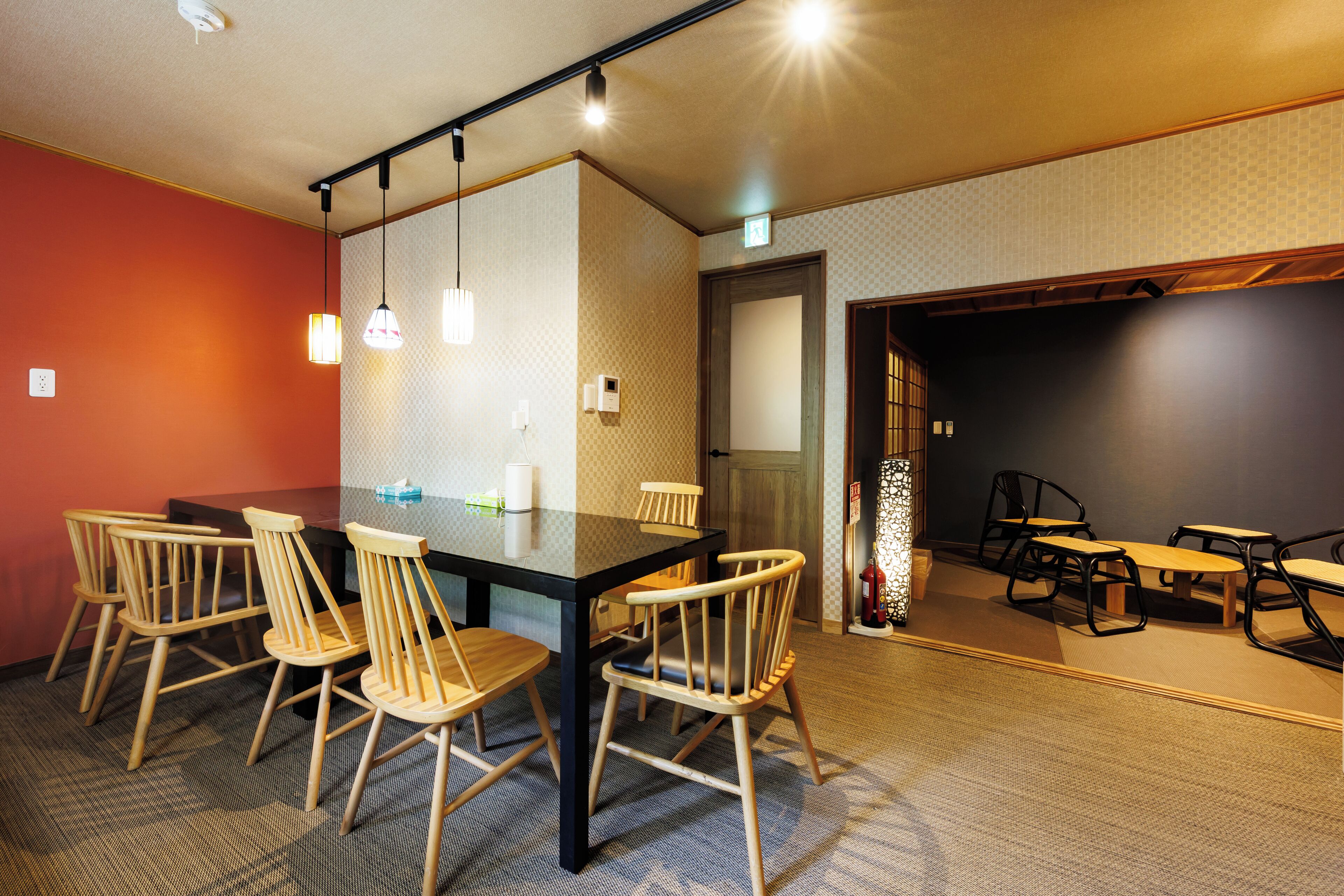 A conference room with a glass table, wooden chairs, and pendant lighting.