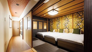 A hotel room with a wooden floor, a bed with a green pillow, a wall with a floral pattern, and a ceiling with wooden beams and a light fixture. - R-Guest Residence Tsurumibashi (Osaka)