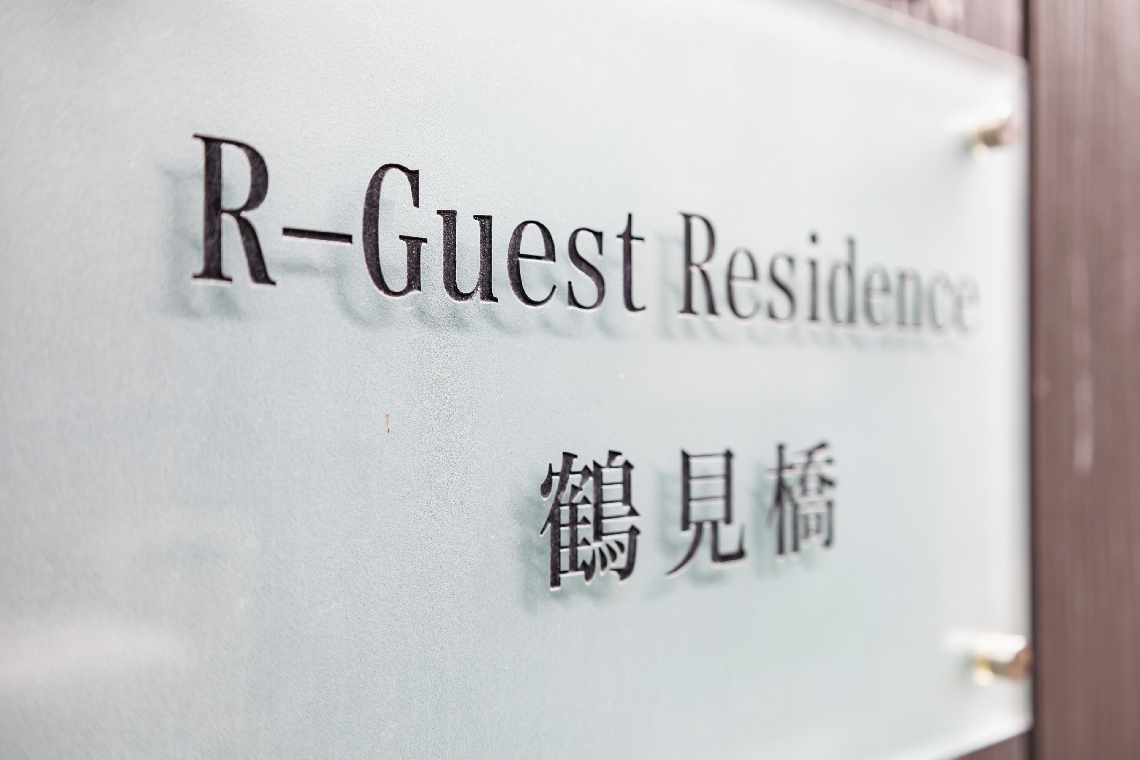 Une enseigne indiquant « R-Guest Residence » et comportant des caractères chinois.
