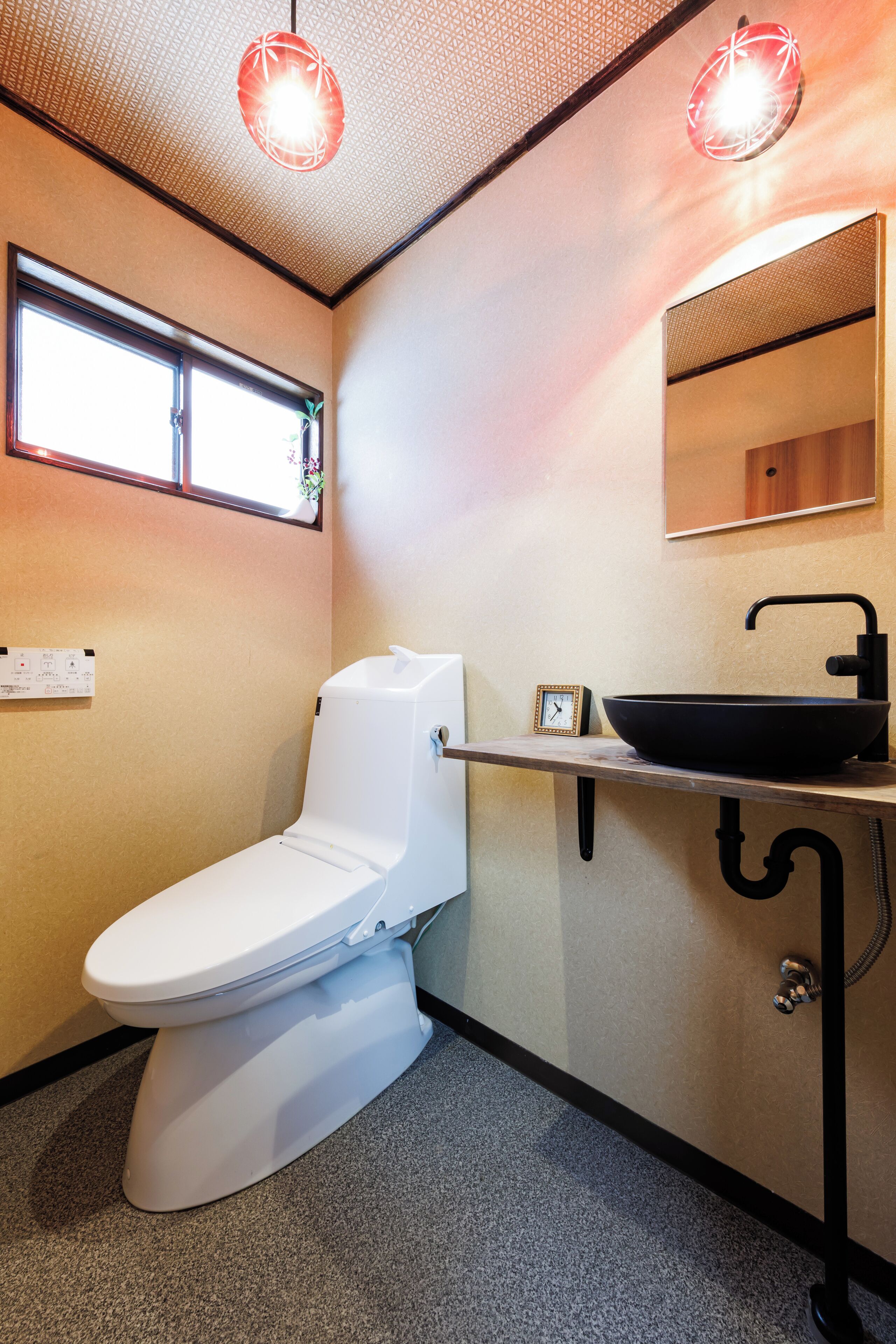 A modern bathroom with a white toilet, a black sink, and a mirror above it.
