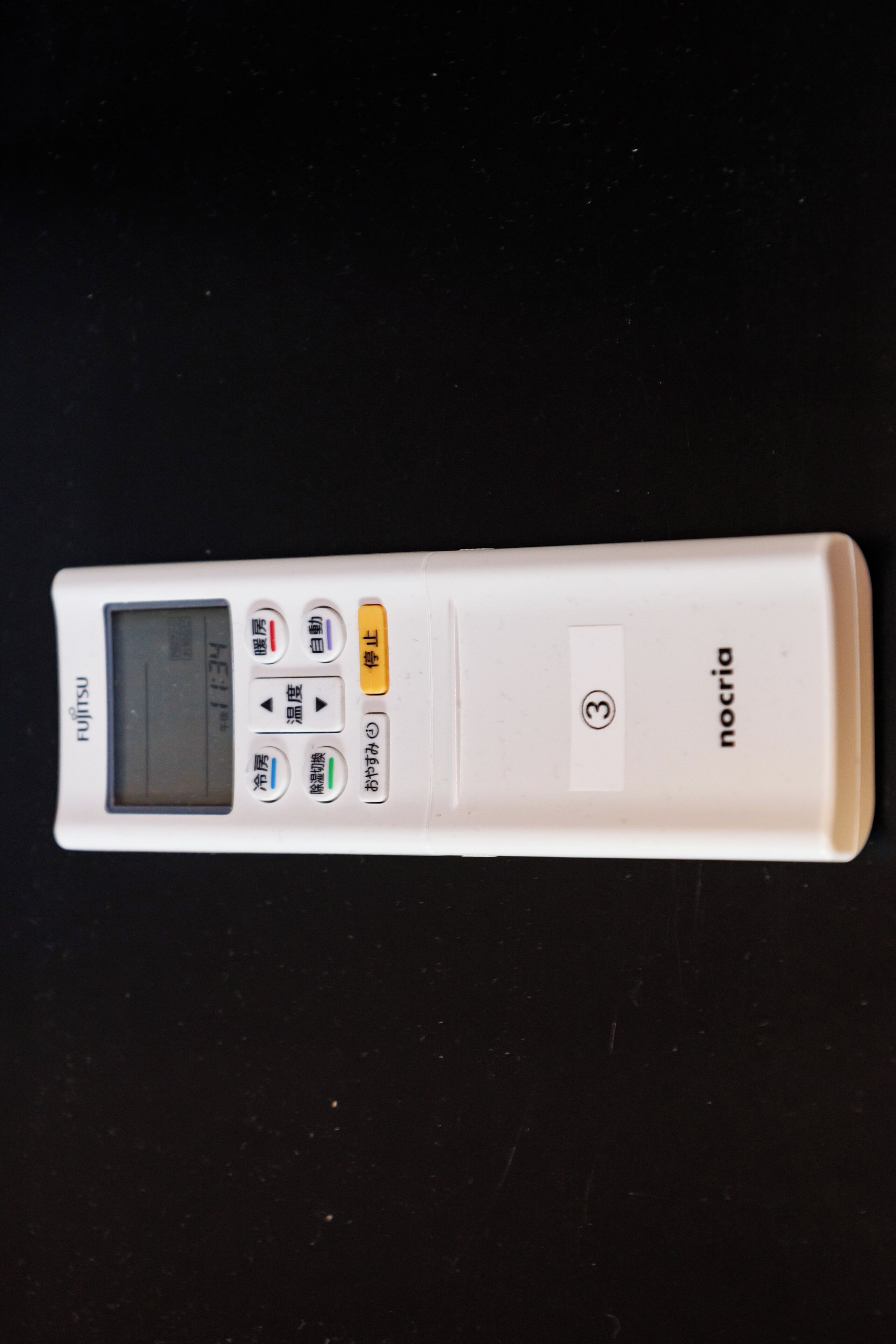 Et hvidt Fujitsu Nocria digitalt ur med display og flere knapper.