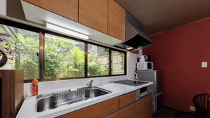 A compact kitchen with a sink, microwave, and refrigerator. - R-Guest Residence Tsurumibashi (Osaka)