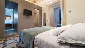 Una habitación de hotel con cama, televisión, vestidor y baño con espejo.