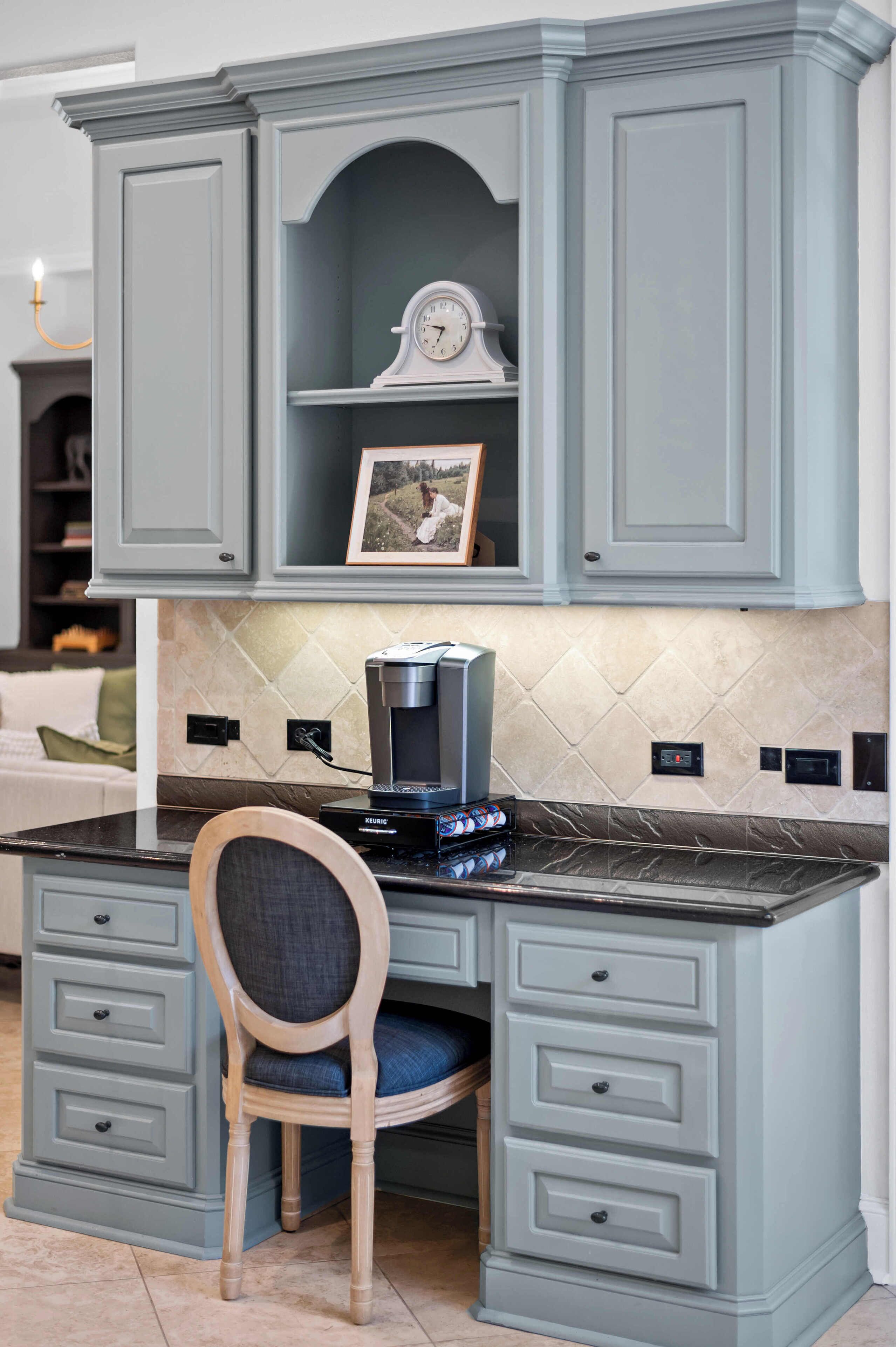 A kitchen with light blue cabinetry, a coffee maker, and a chair.