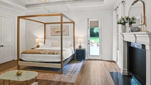 Ein Schlafzimmer mit einem Himmelbett, einem Glastisch, einem Kamin und Blick ins Freie.