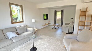 A modern living room with a sofa, armchair, coffee table, and a TV on the wall. - Apartment for 6people - Air conditioning - Litlle sea view - Wifi - Sainte Maxime (STE MAXIME)
