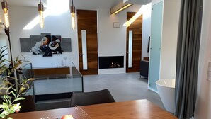 A modern living room with a fireplace, a dining table with fruit, and a staircase.