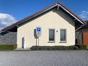 Un bâtiment avec un panneau indiquant un parking, deux fenêtres et un mur en pierre.