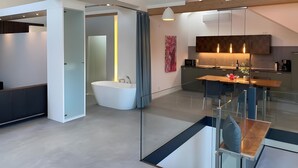 A modern kitchen with a dining area, a large window, and a built-in bathtub.