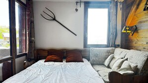 Une chambre à coucher avec un lit, un canapé, une fenêtre et une lampe fixée au mur.