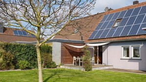 Una casa con techo de paneles solares, un patio cubierto y un césped cuidado.