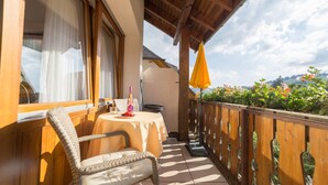 A balcony with a wicker chair, a small round table, and a yellow umbrella. - Hotel-Pension Enzian – Double Room with Balcony or Terrace, Breakfast Included (Todtnau)