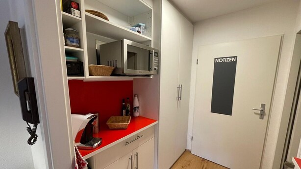 A compact kitchen with white cabinets, a microwave, a red countertop, and a door labeled 'NOTIZEN'. - Studio 'Inzell mit Mountain View' with Balcony and Wi-Fi (Inzell)