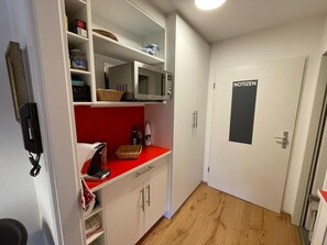 A compact kitchen with white cabinets, a microwave, a red countertop, and a door labeled 'NOTIZEN'. - Studio 'Inzell mit Mountain View' with Balcony and Wi-Fi (Inzell)