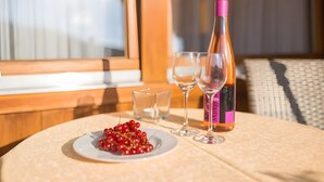 A table with a bottle of wine, two glasses, and a plate of red berries.
