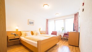 A hotel room with a wooden bed, bedside tables, a desk, and a chair. - Hotel-Pension Enzian: Double Room with Balcony or Terrace, Breakfast Included (Todtnau)