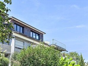 A modern two-story house with a balcony, large windows, and a garage.