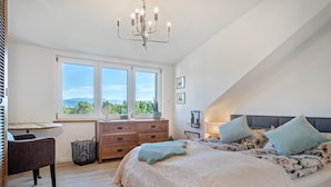 Une chambre avec un grand lit, un bureau et une fenêtre donnant sur un beau paysage.