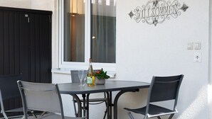 Et udendørs bord med to stole, en flaske og et glas på bordet.