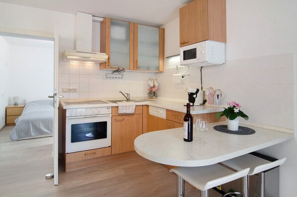 Una cocina funcional con microondas, horno y un pequeño comedor con mesa y sillas.