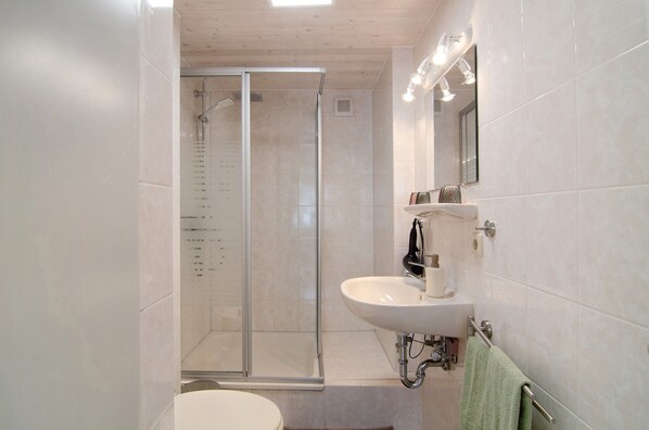 Une salle de bain moderne avec une douche à parois de verre, un lavabo et un miroir.