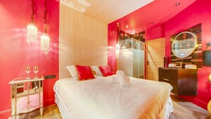 Una habitación de hotel con una cama grande, un tocador con espejo y una pared de acento roja.