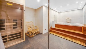 Un baño moderno con una bañera de madera, un sillón de mimbre y un box de ducha de vidrio.