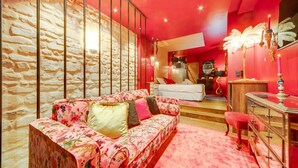 Un dormitorio con pared de piedra, sofá floral, cama y tocador con espejo.