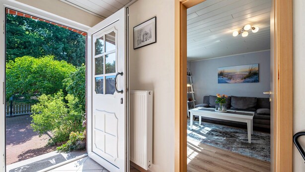 A room with a white radiator, a white table, a grey sofa, and a painting on the wall. - Apartment 'Gemütliche' with Shared Terrace, Shared Garden and Wi-Fi (Cuxhaven)