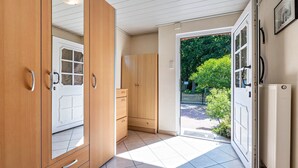 A room with wooden cabinets, a white door, and a view of greenery outside. - Apartment 'Gemütliche' with Shared Terrace, Shared Garden and Wi-Fi (Cuxhaven)