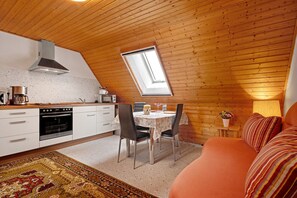 Una cocina acogedora con comedor, un sofá y una pequeña mesa con lámpara.