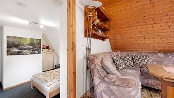 Ett mysigt rum med ett trÀpanelat tak, en soffa, ett litet bord och en golvlampa.