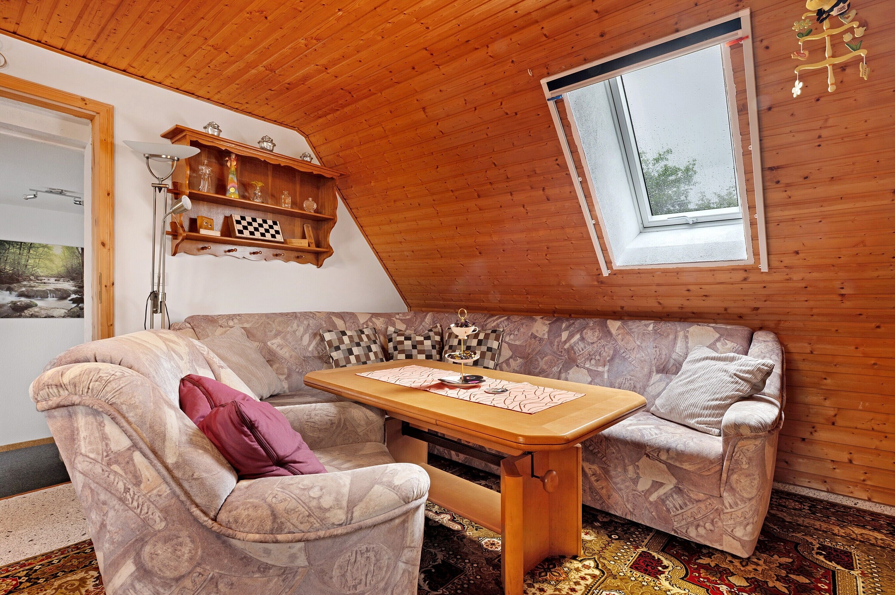 Une pièce chaleureuse avec un plafond en bois, un canapé, une table et une fenêtre.