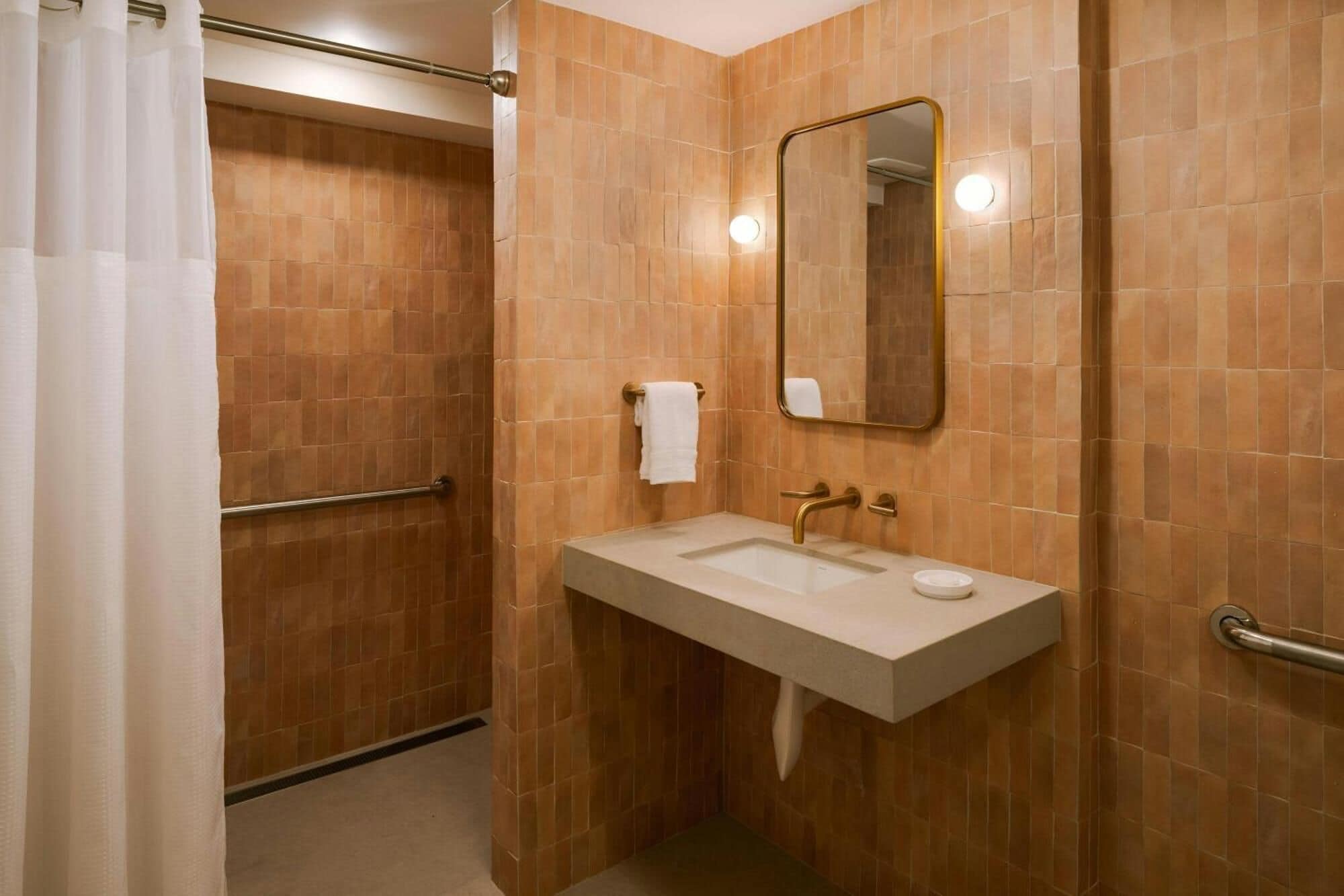 A bathroom with a shower, a sink, a mirror, and a towel rack.