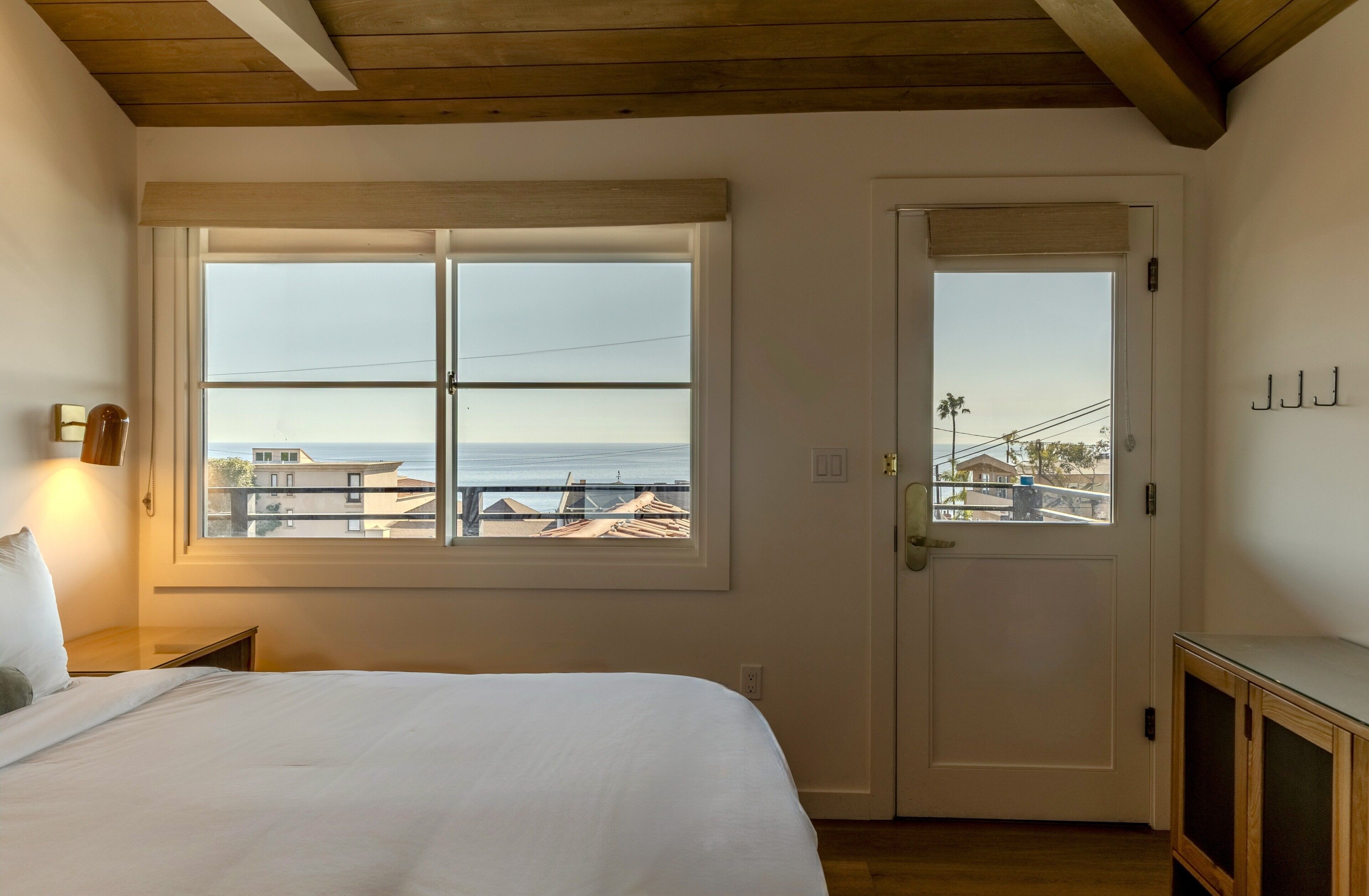 Un dormitorio con un ventanal grande, una puerta y una mesita de noche.