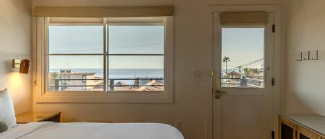 Ein Schlafzimmer mit großem Fenster, einer Tür und einem Nachttisch.