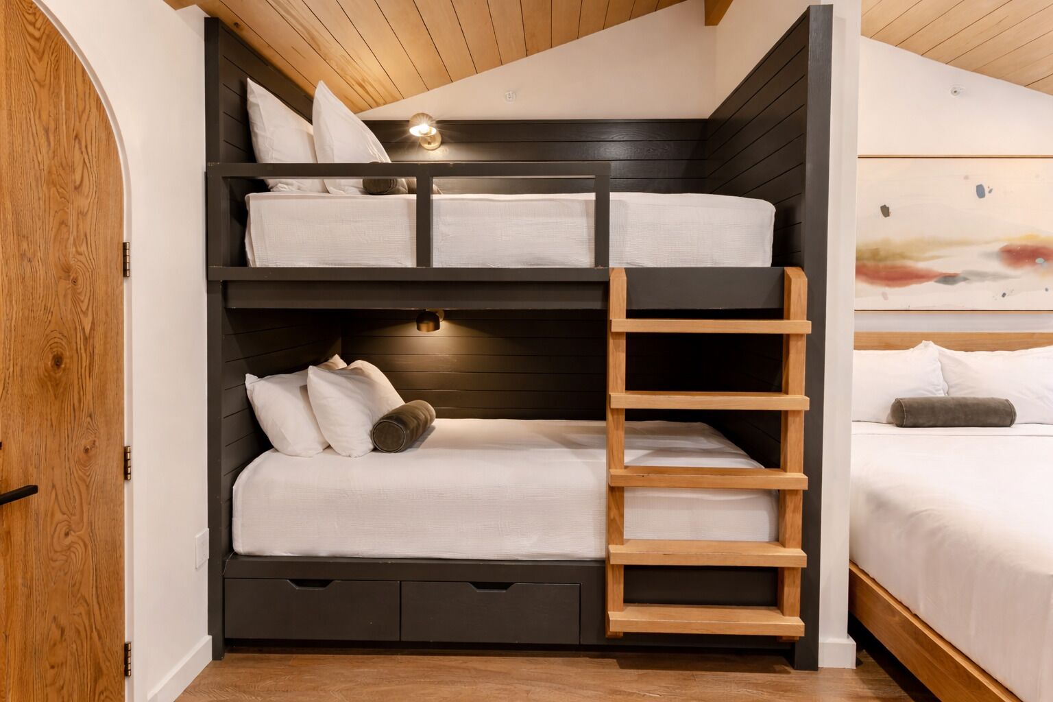A bunk bed with a ladder, a bedside table, and a headboard.