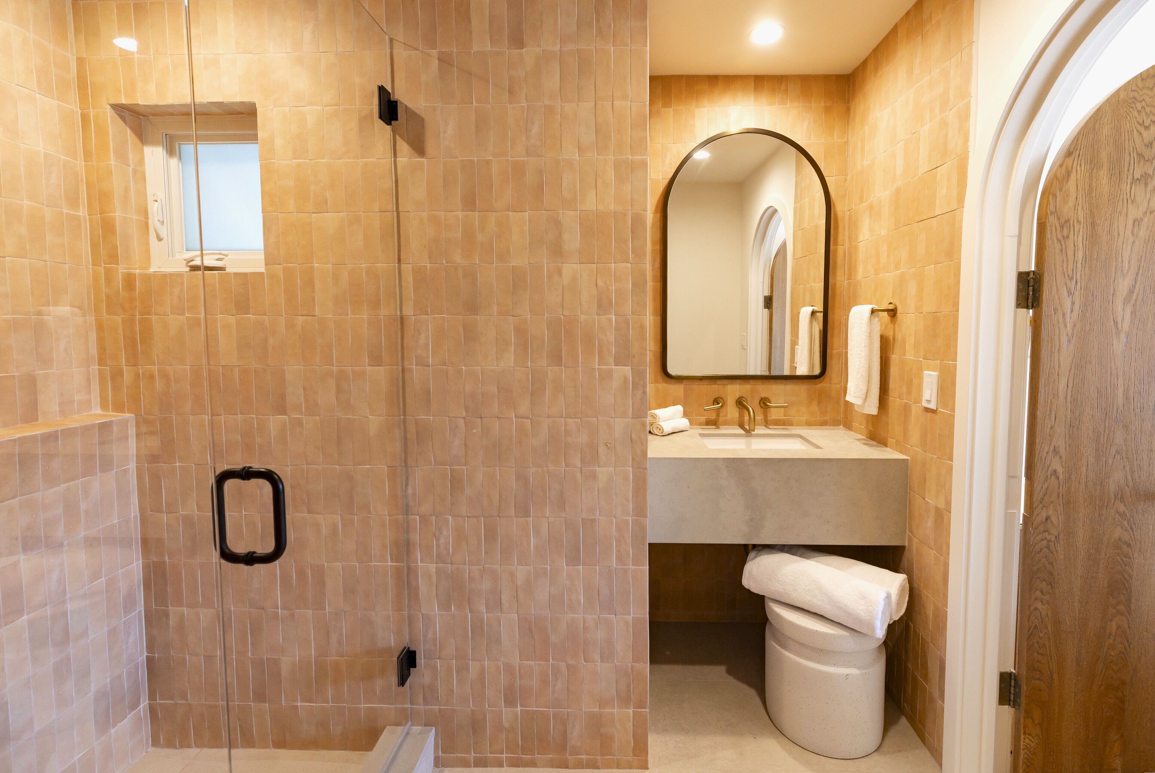 A bathroom with a shower, sink, mirror, and toilet.
