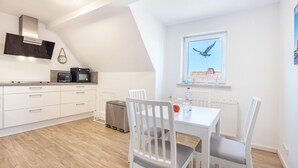 Una cocina moderna con armarios blancos, horno empotrado y ventana con vistas a un pájaro.