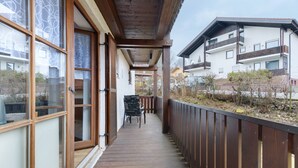 Una terrassa de fusta amb vista a edificis veïnals, una cadira i una tanca.