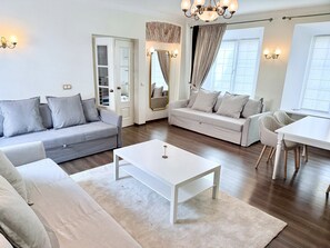 Un salon moderne avec un canapé gris, une table basse blanche et un coin repas comprenant une table et des chaises blanches.