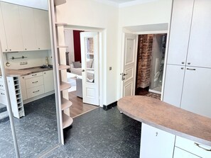 A modern kitchen with white cabinets, a marble countertop, and a built-in oven. - Pilies8 Luxury Vilnius Apartment (Vilnius)