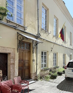 A building with a wooden door, a brick wall, and a flag. - Pilies8 Luxury Vilnius Apartment (Vilnius)