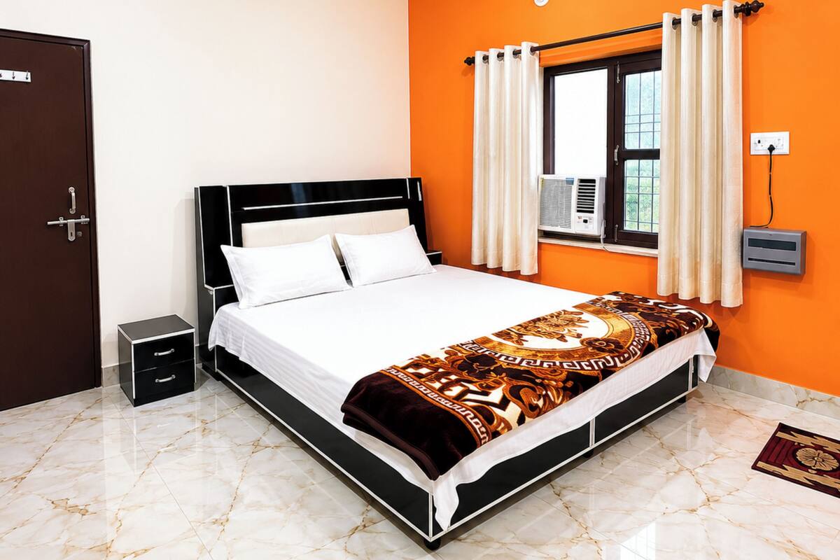 A bedroom with a bed, a ceiling fan, a window with curtains, an air conditioning unit, and a door.